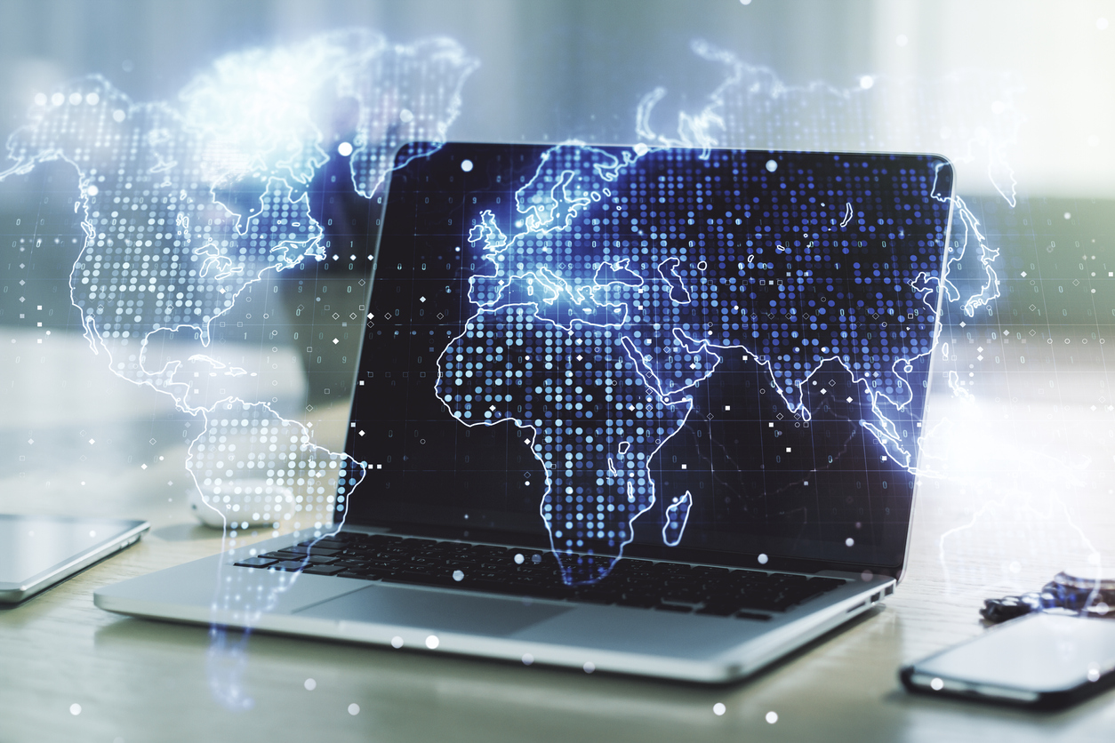 Digital world map with blue dots across different points on it, in front of a laptop computer