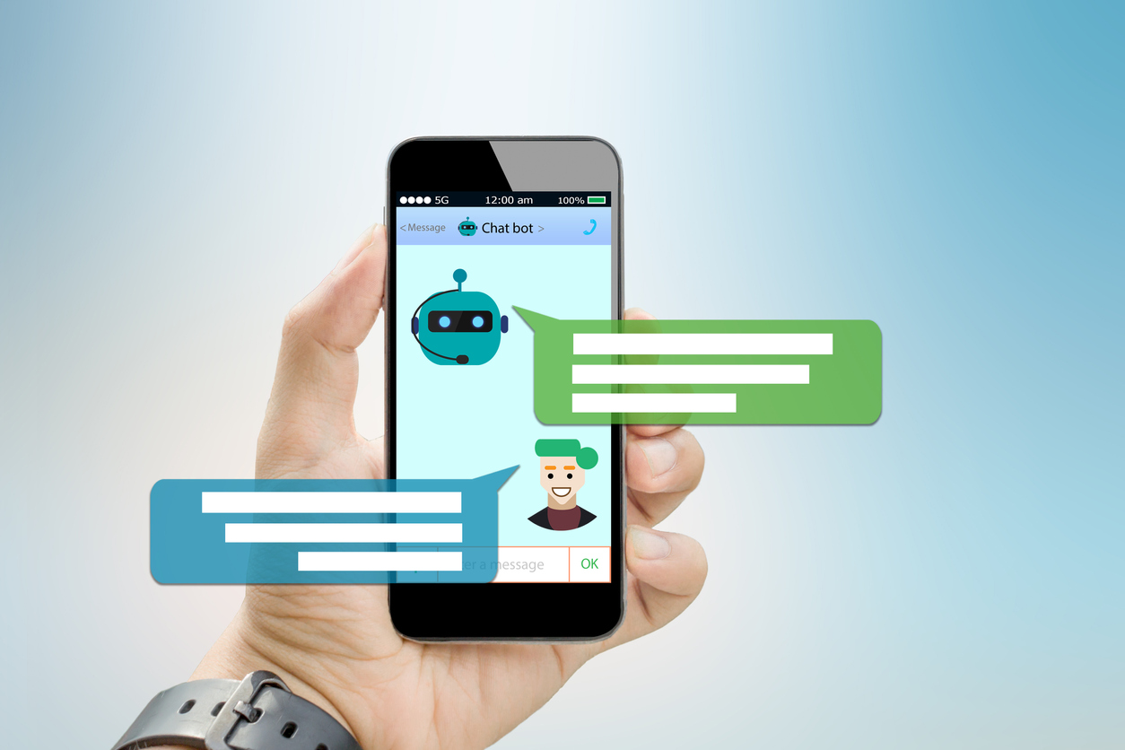 A man holds a mobile phone in his hand. On the screen, a chat is taking place between him and a chatbot.
