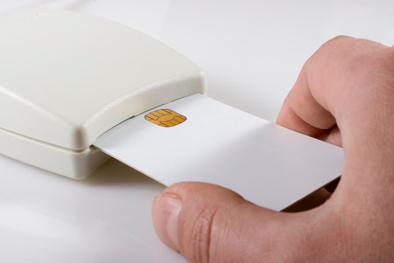 This photo shows a plastic box with a slot in it. A man’s hand is inserting a smart card into the slot.