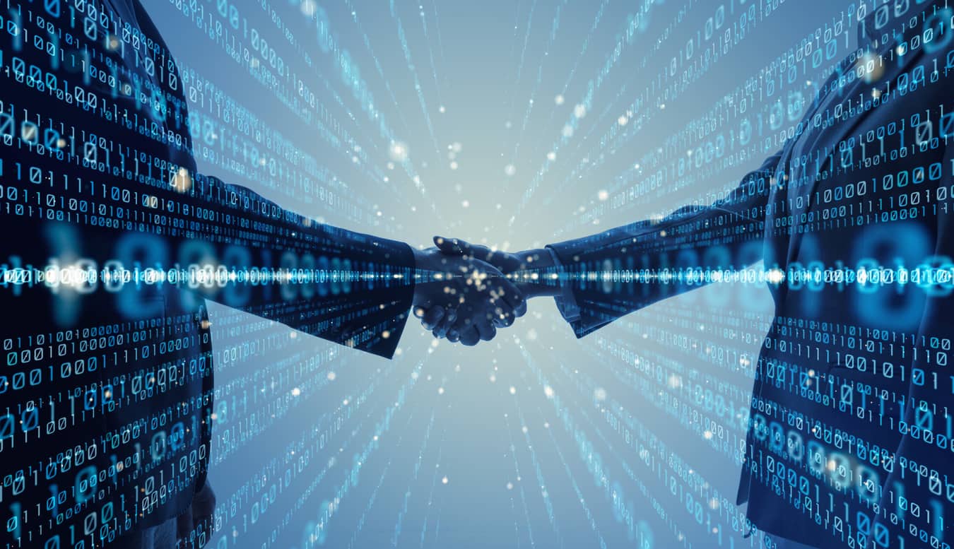 This image shows two businesspeople shaking hands. Superimposed are glowing rows of binary code. This image is meant to represent a technological partnership.