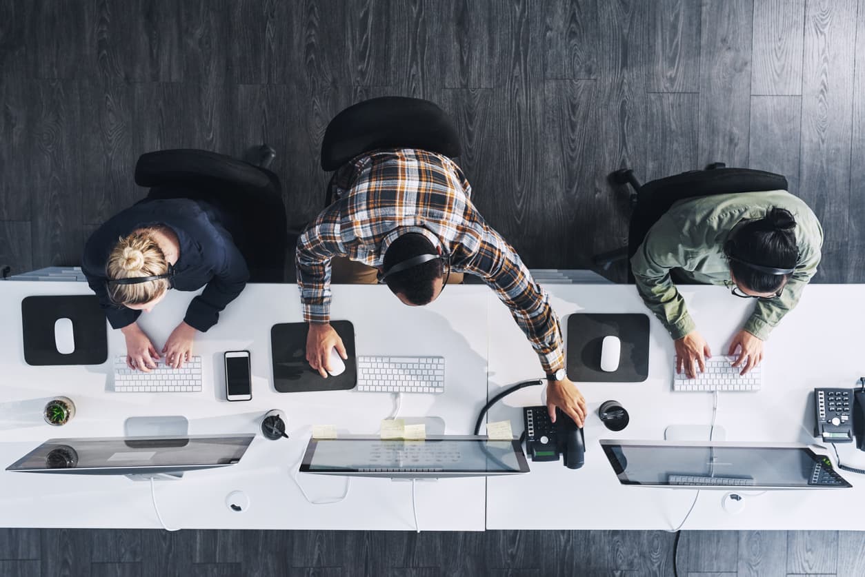 Three agents working at a call center desk.