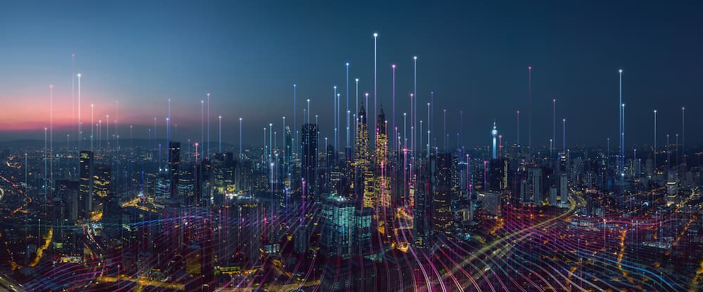 Colorful big city photo in blue with digital communication lines of various colors representing digital virtual connections overlaying the cityscape