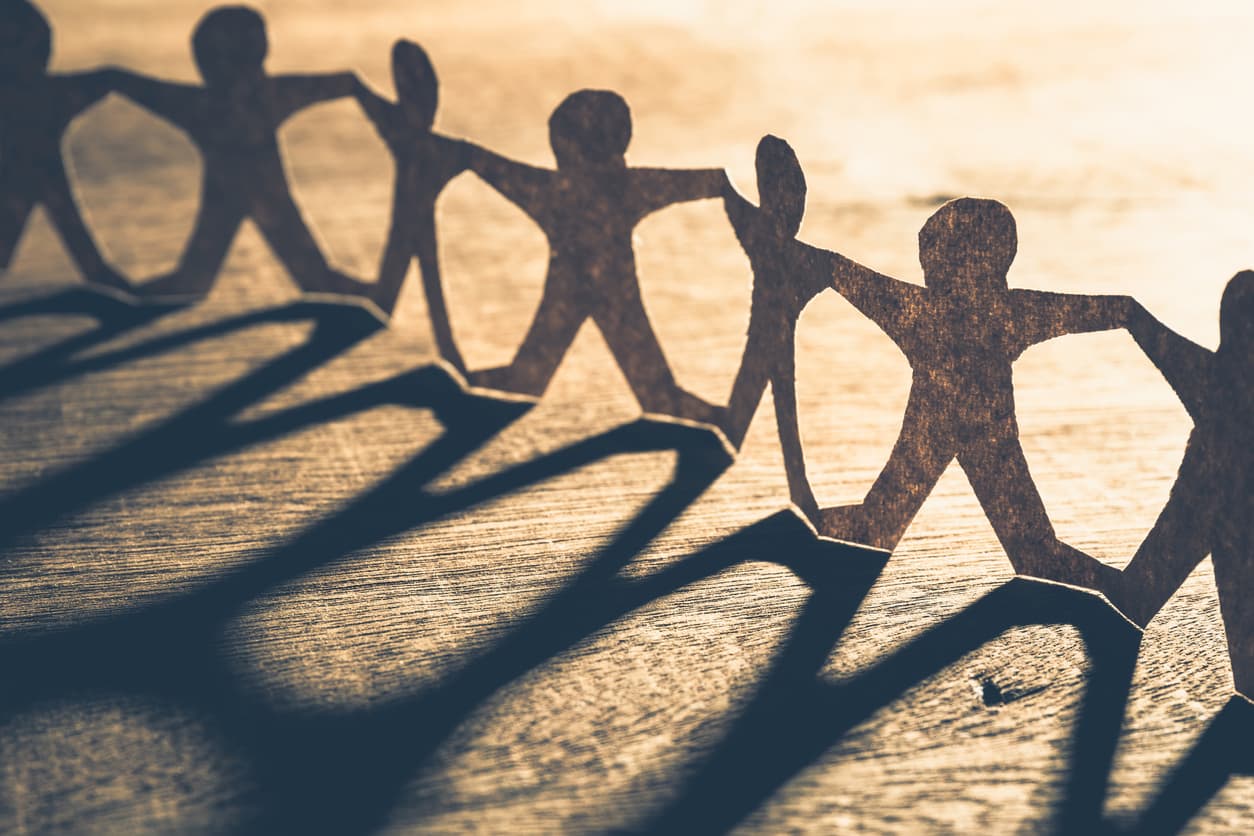 Light brown paper-like background with paper people cutouts linked together in a chain.