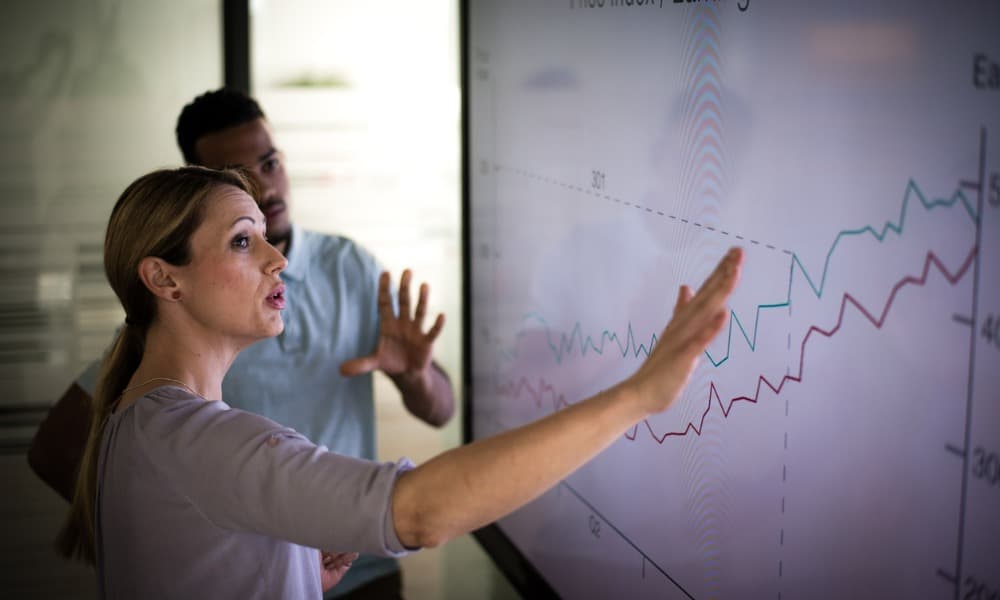 Two employees review business growth metrics and discuss contact-center-as-a-solution service and using a ConnectPath dashboard for their business.