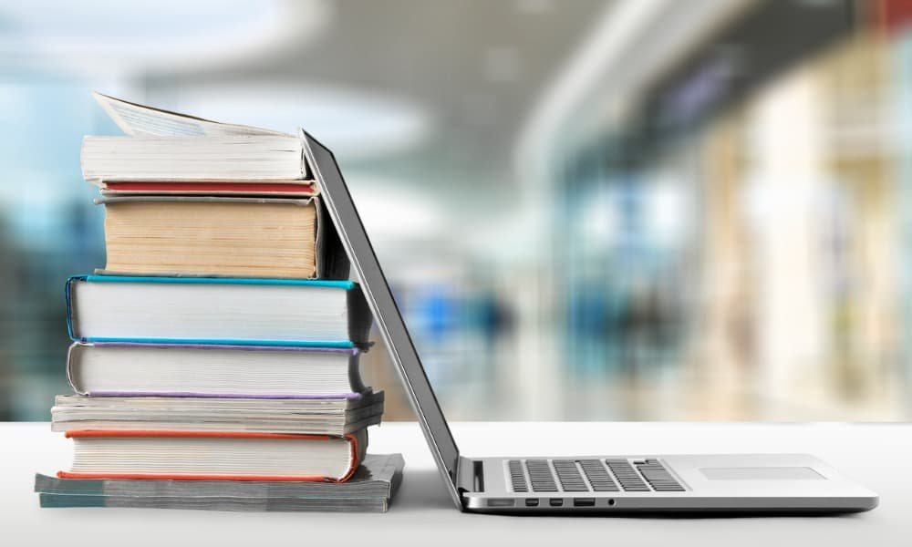 A remote learning space with an office and a desk with a laptop opened against a stack of hardcover books