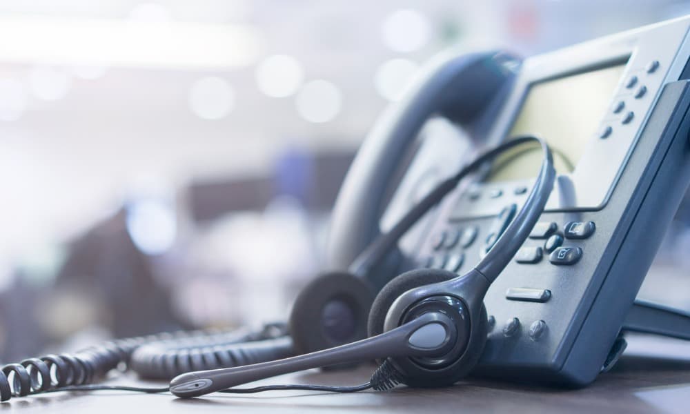 A close-up photo of a call center headset and VOIP telephone